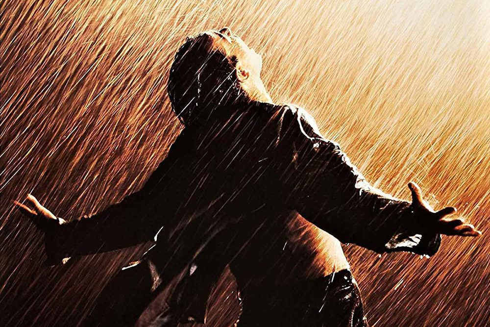 The man gets wet in the rain, but he embraces his arms and feels the rain.